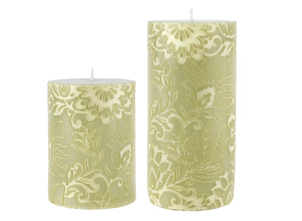 Two green patterned candles on a white background