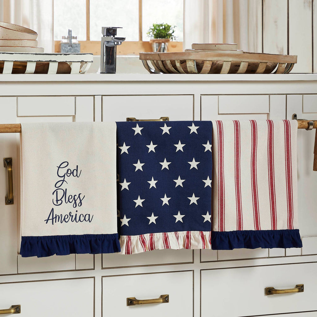 Three kitchen towels with patriotic designs hanging on a rack.