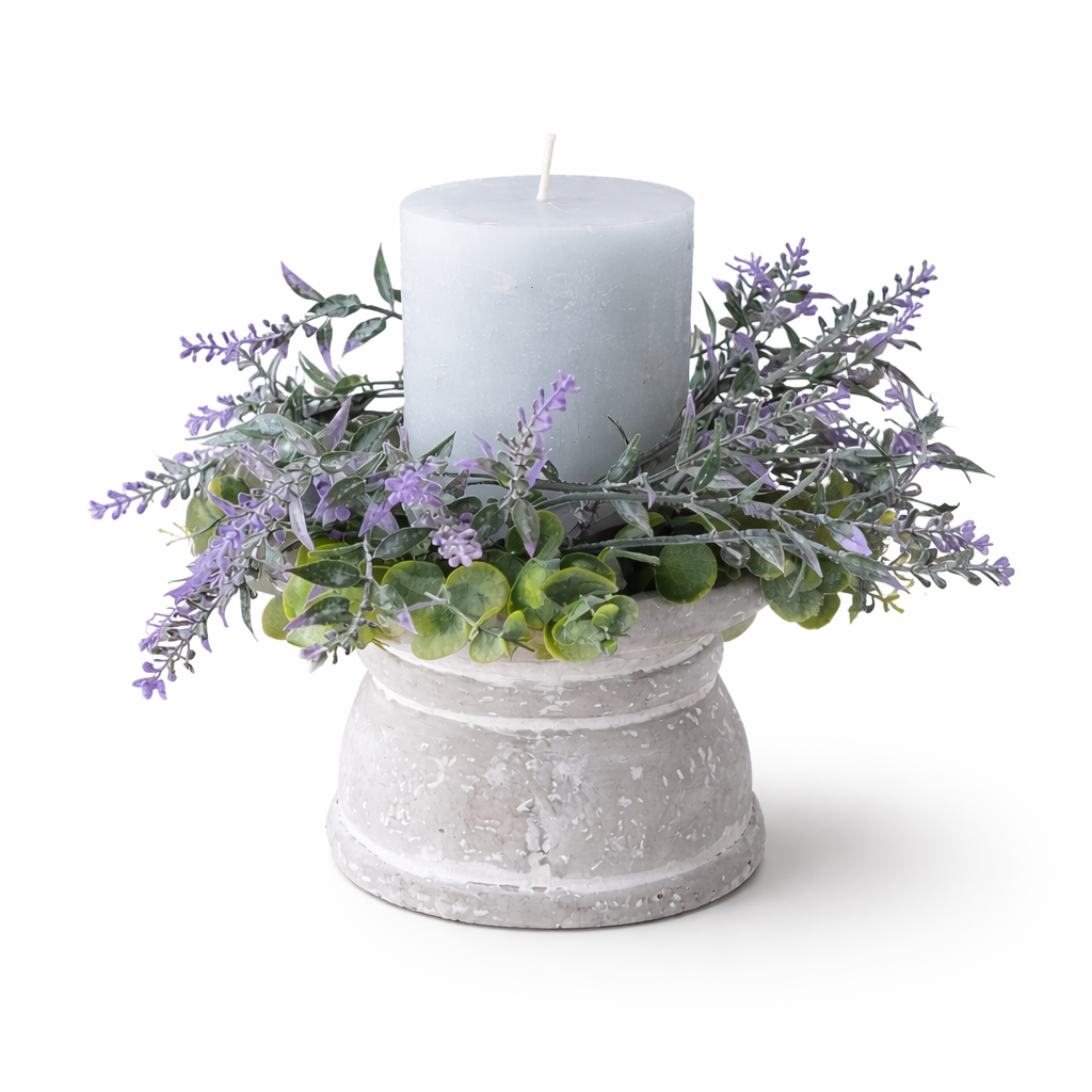 Decorative arrangement with a white candle in a concrete holder surrounded by lavender and greenery on a white background