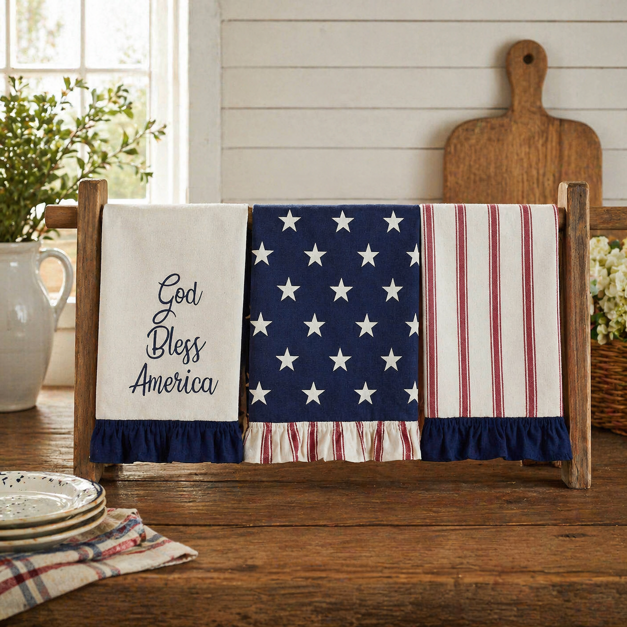 American flag-themed towels and 'God Bless America' towel on a wooden towel rack with a rustic background.