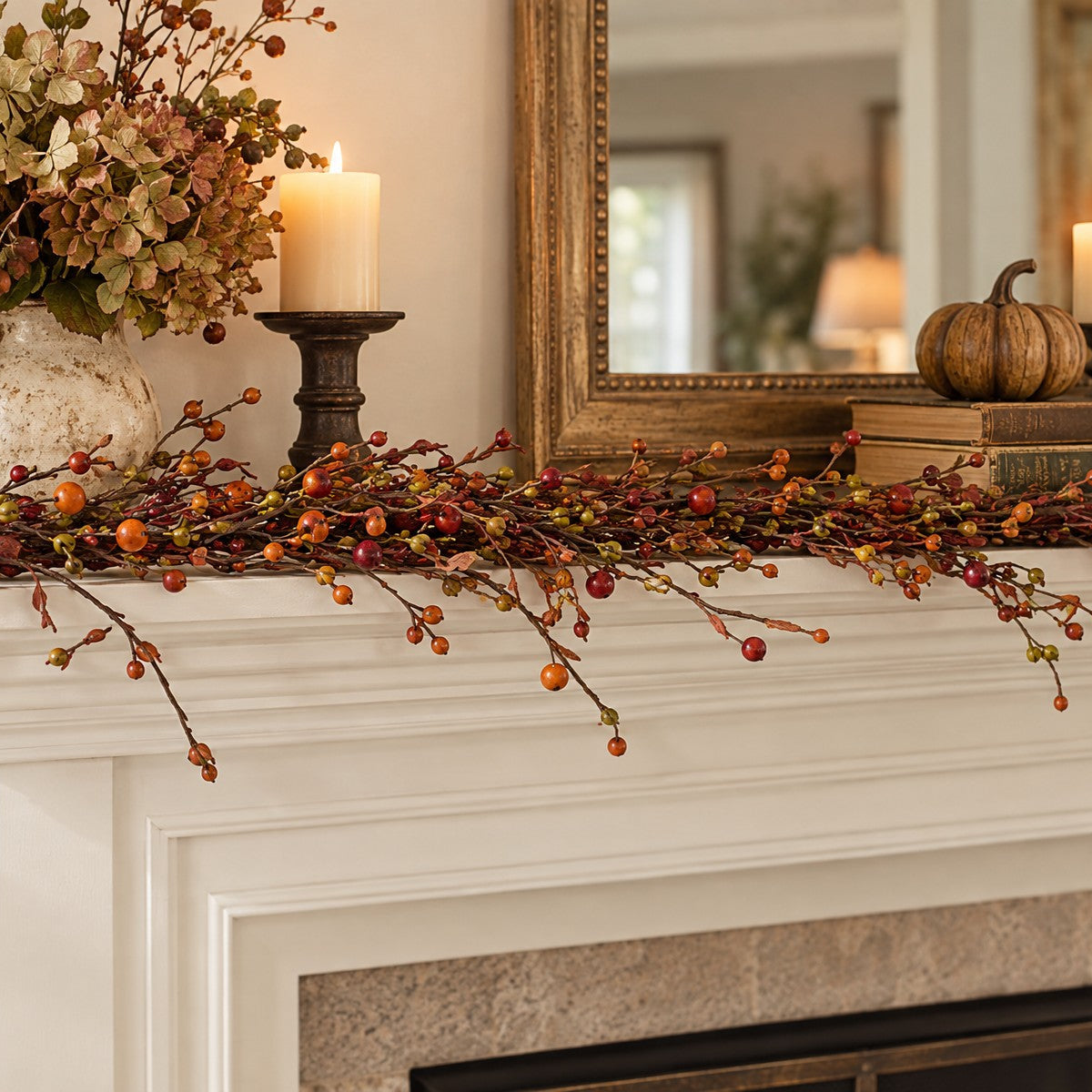 A decorative fall berry garland with red and orange berries and small acorns draped across a white fireplace mantel, styled with a vase of dried flowers, lit candles, a small pumpkin, and a mirror in a cozy indoor setting.