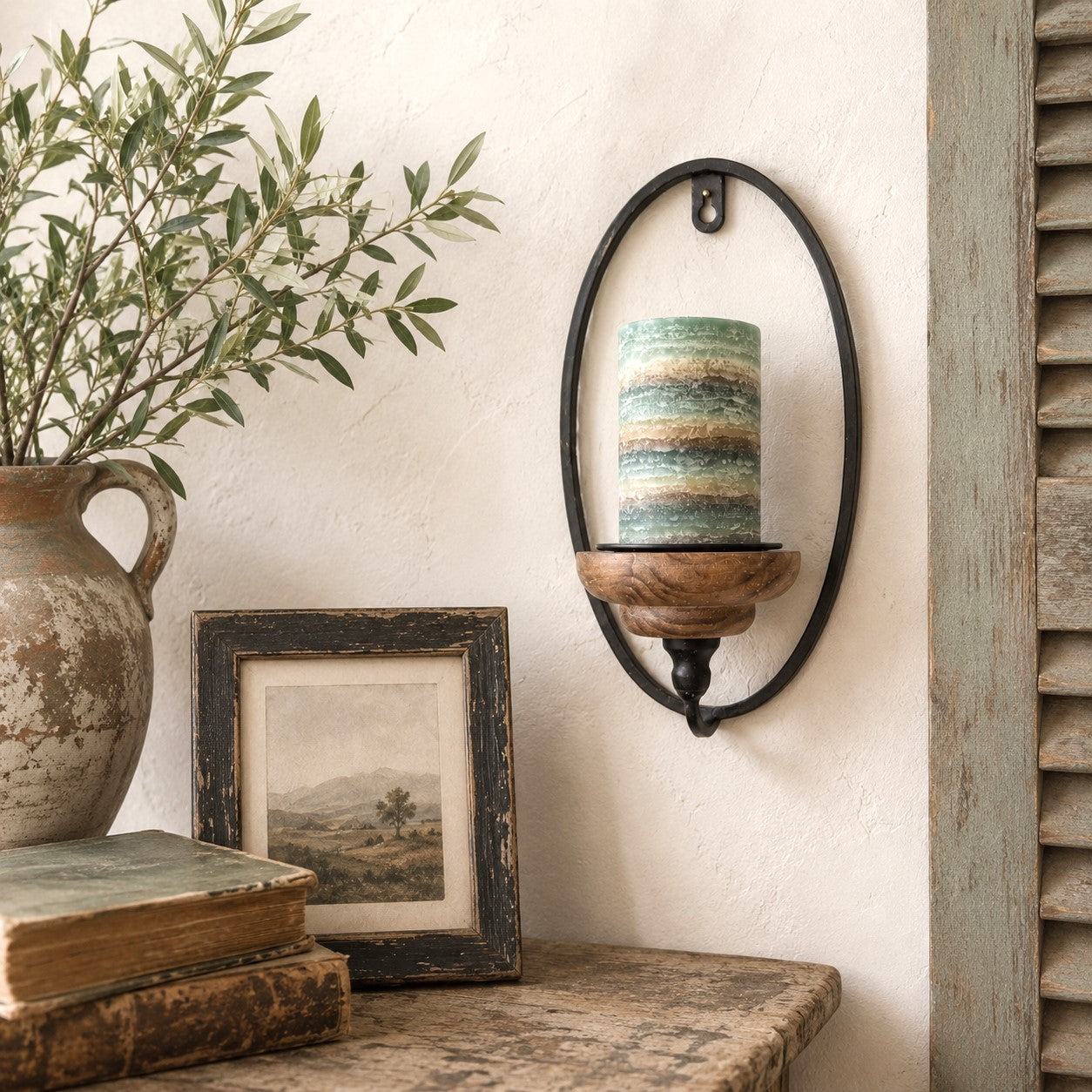 Decorative wall sconce with a candle, framed picture, and vase on a shelf.