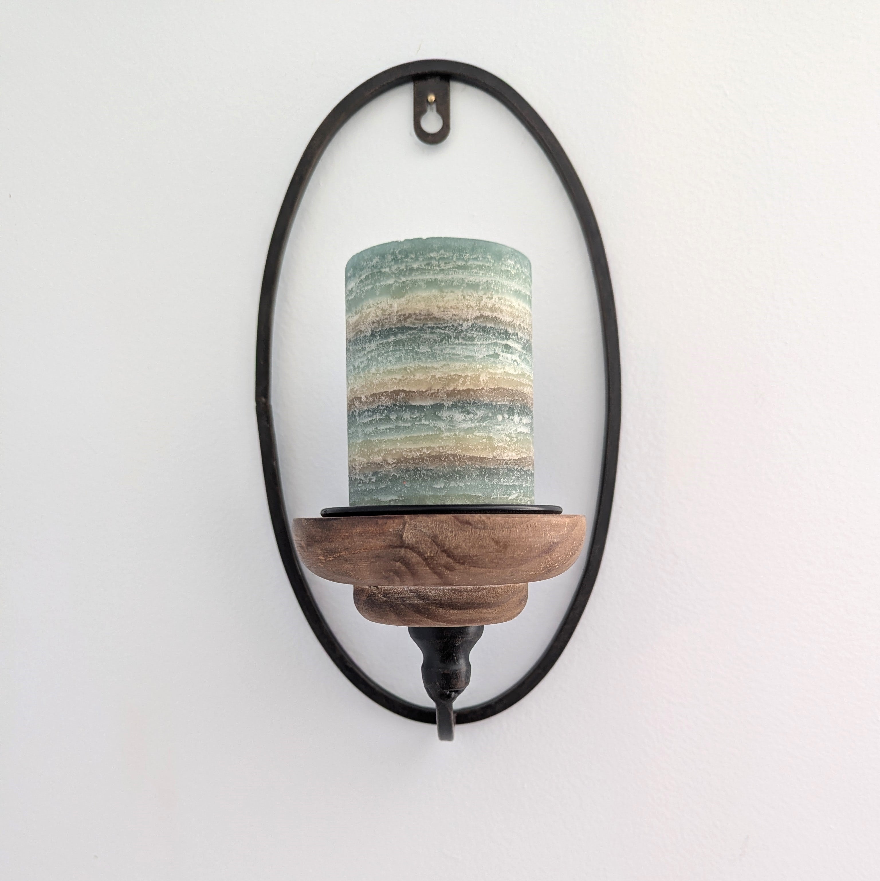 Wall-mounted candle holder with a wooden base and marbled green and brown candle on a white background