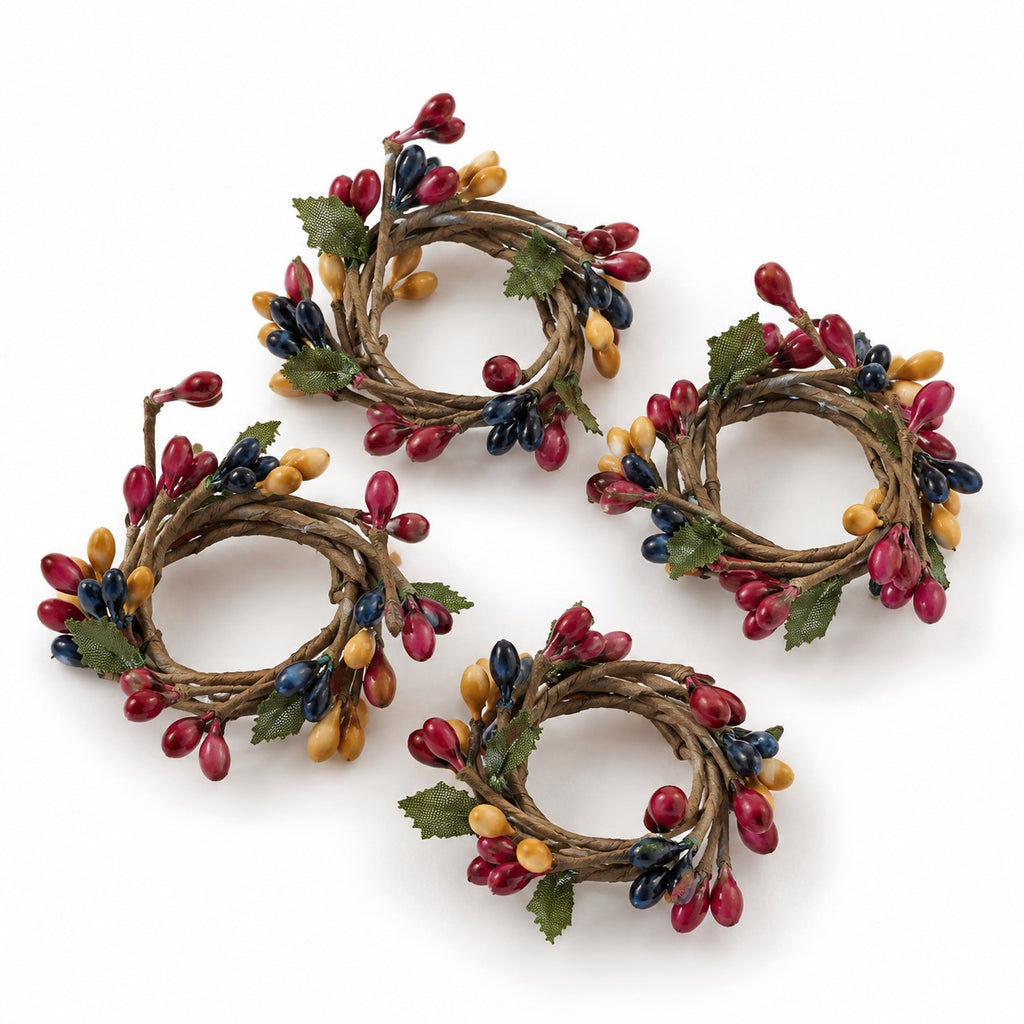 Four rustic grapevine wreaths decorated with red berries, yellow acorns, and green leaves, arranged on a white background.