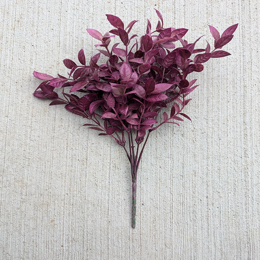Bouquet of purple artificial leaves on a textured beige background