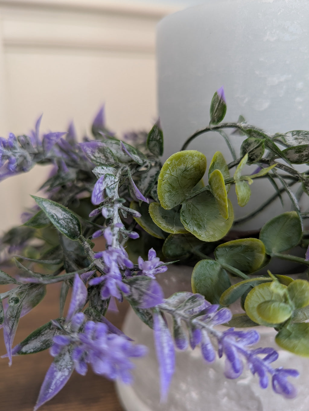 Artificial plants with lavender-like flowers and green leaves in a white pot.