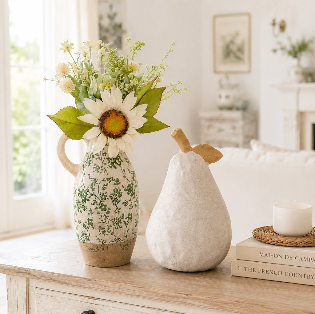 Decorative vase with flowers and a pear-shaped object on a wooden surface in a home setting.