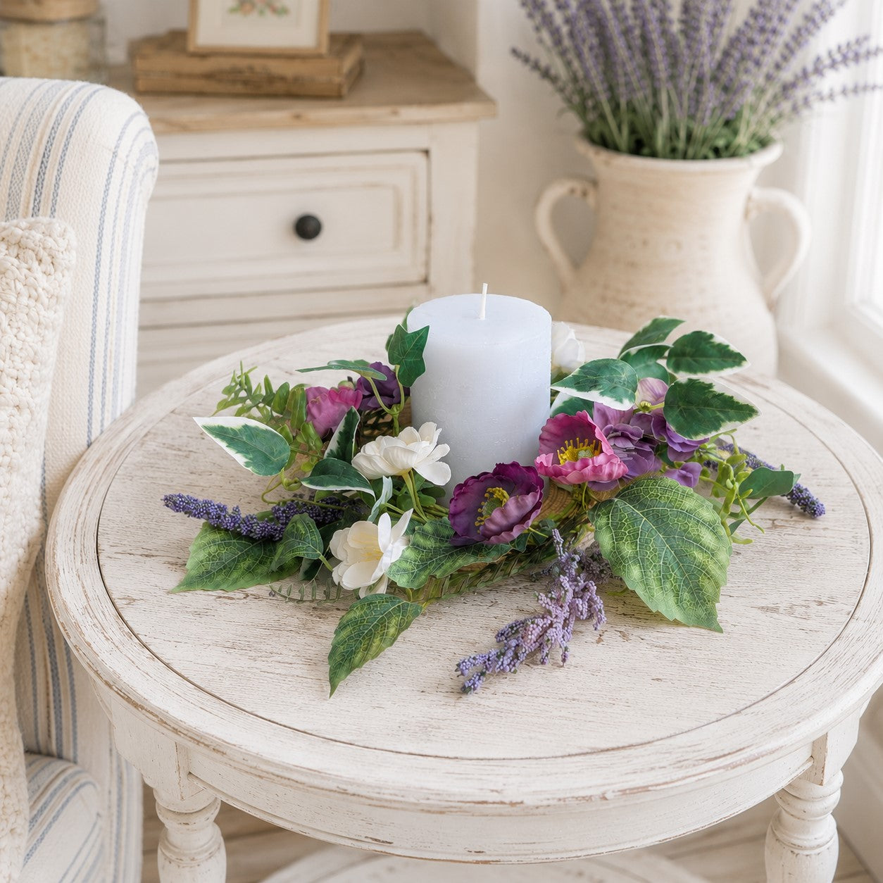 Floral arrangement with a candle on a round wooden table in a home setting