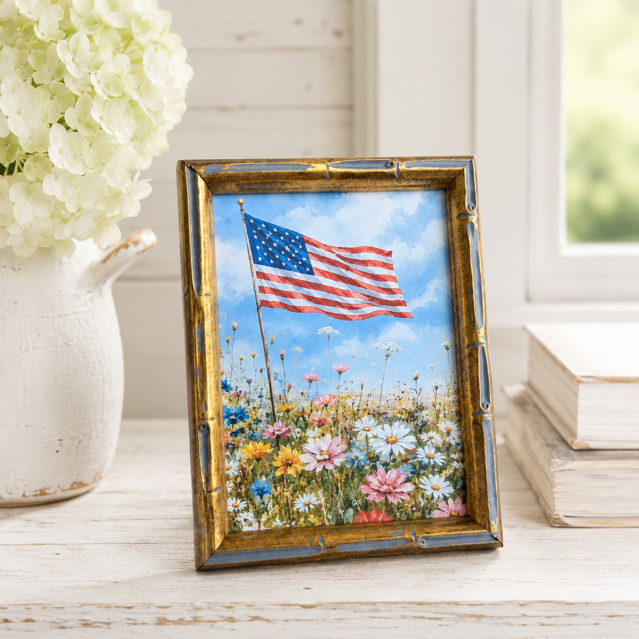 Framed artwork of an American flag in a field of flowers on a wooden surface.