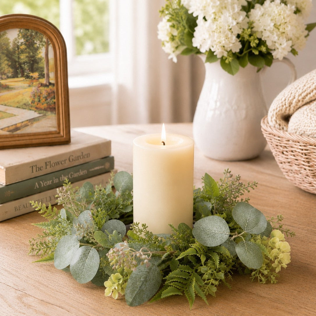 Decorative setup with a candle, floral arrangement, and books on a wooden surface.
