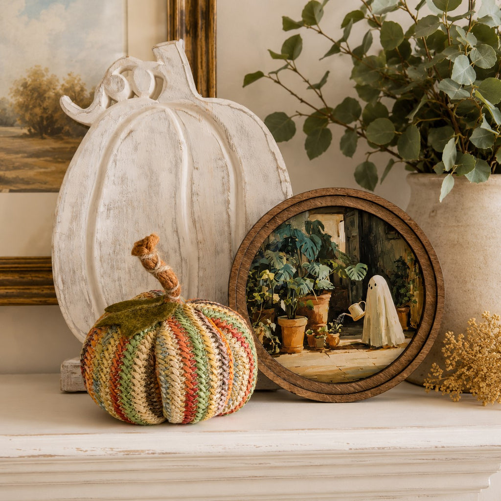 Round framed ghost gardener artwork displayed on a mantel with rustic pumpkins and autumn décor in a cozy farmhouse setting.