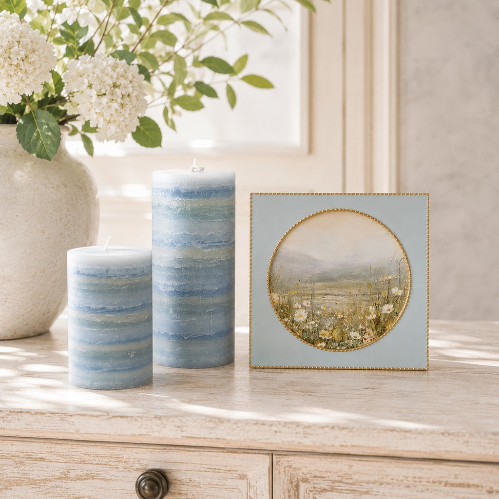 Decorative candles and a framed picture on a wooden surface with a blurred background