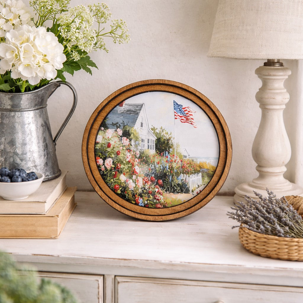 Decorative plate with a garden scene on a shelf with flowers and a lamp.